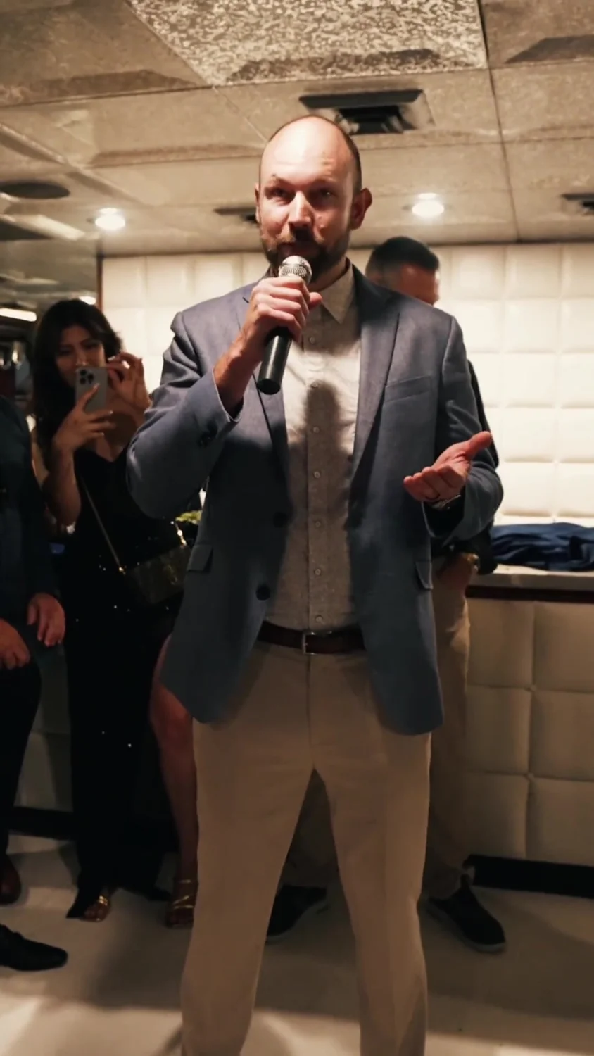 Shawn speaking into a microphone at a real team celebration